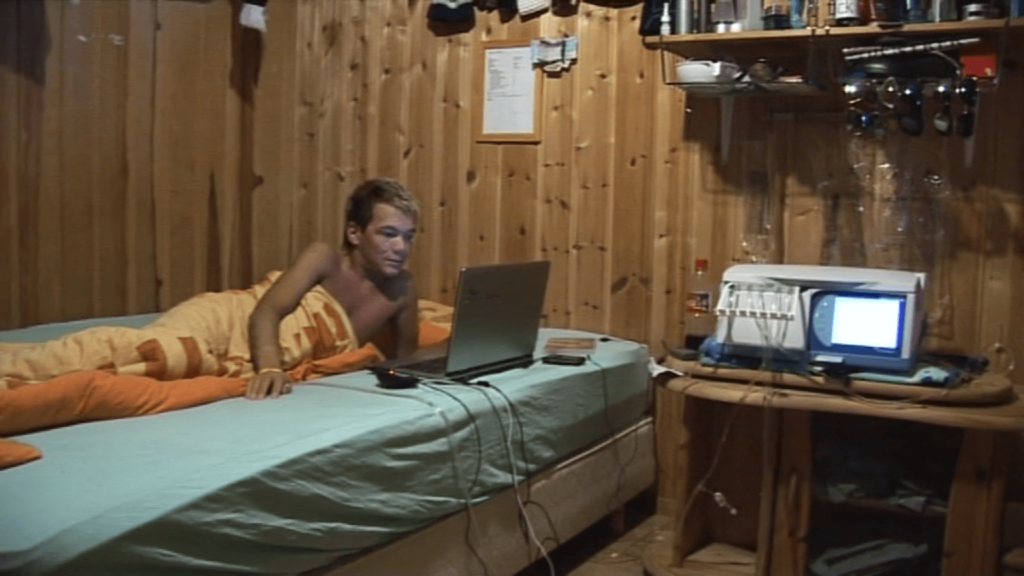 Bilde av en ung Jan Erik som ligger på sengen og spiller pc mens han er tilkoblet dialysemaskinen. 