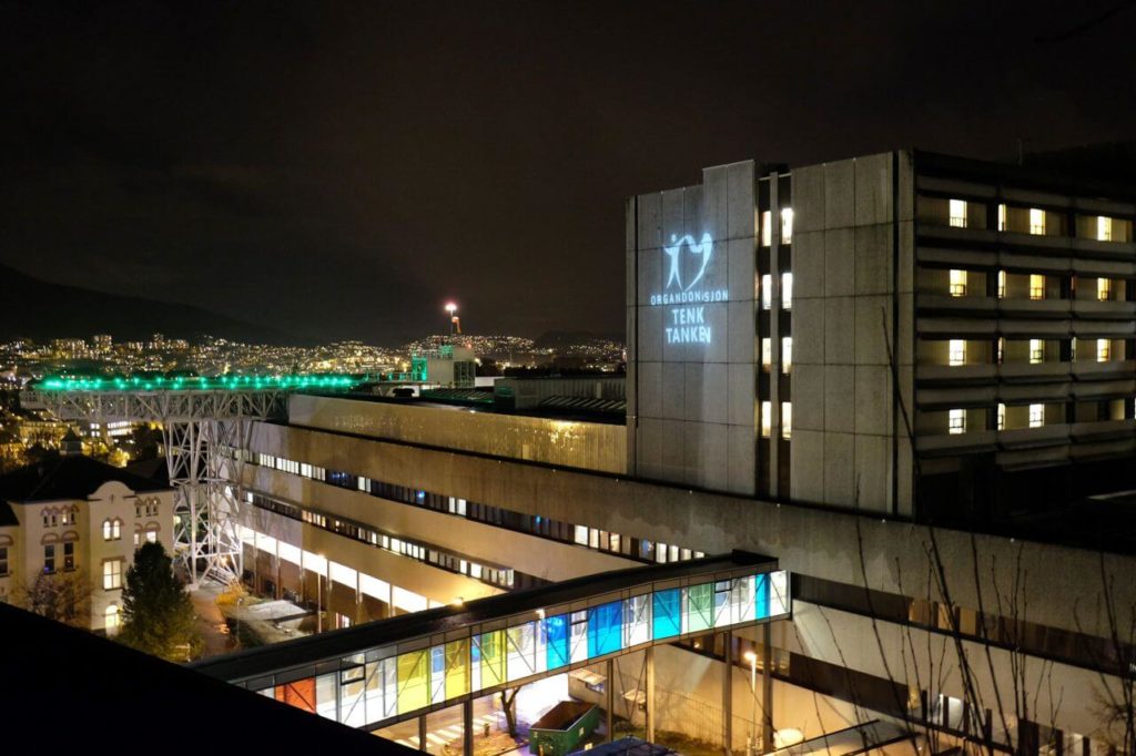 Bilde av Haukeland Sykehus i mørket, hvor logoen til Stiftelsen Organdonasjon lyser opp på veggen.