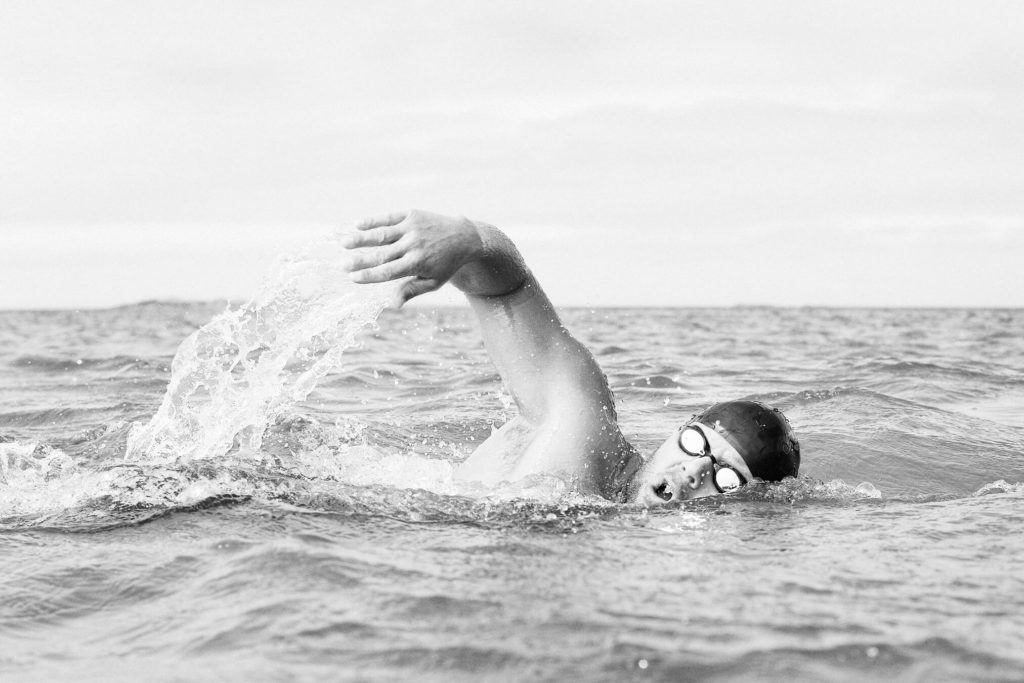 Sort/hvitt-bilde av Stian Vikra som svømmer i sjøen.